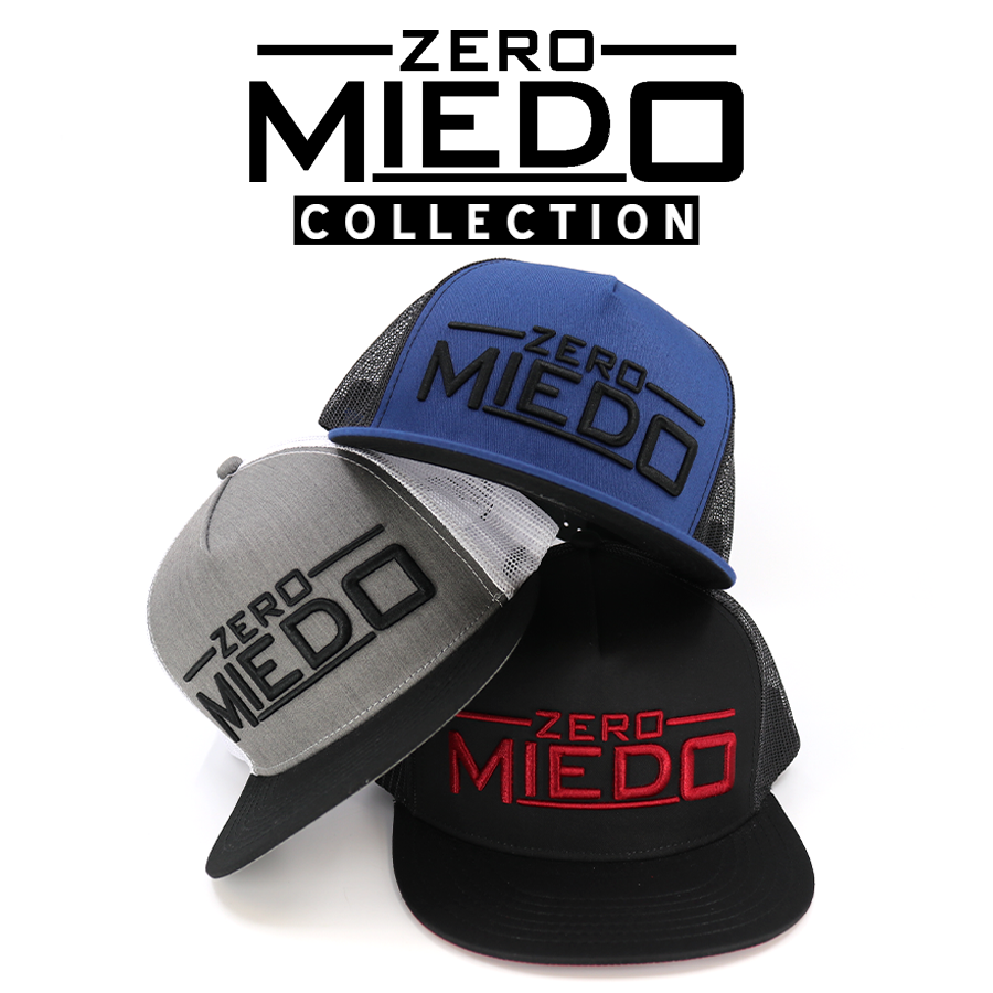 Zero Miedo Collection: Stacked blue, grey, and black trucker hats with embroidered logos.