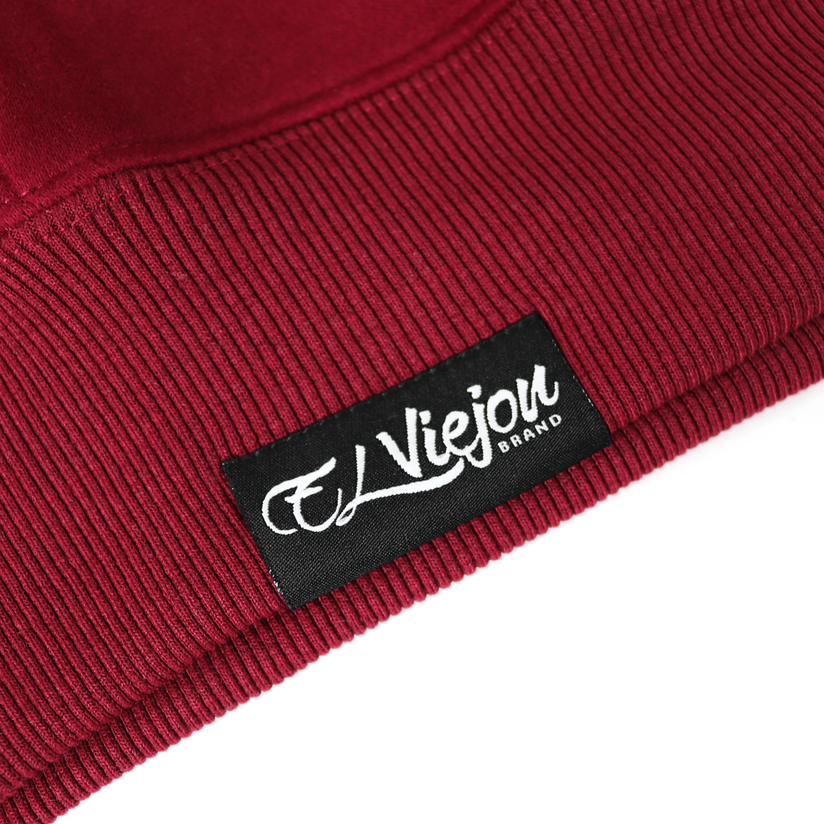 Close-up of a maroon cotton/poly fleece hoodie with a black "El Viejou Brand" label on the ribbed hem.