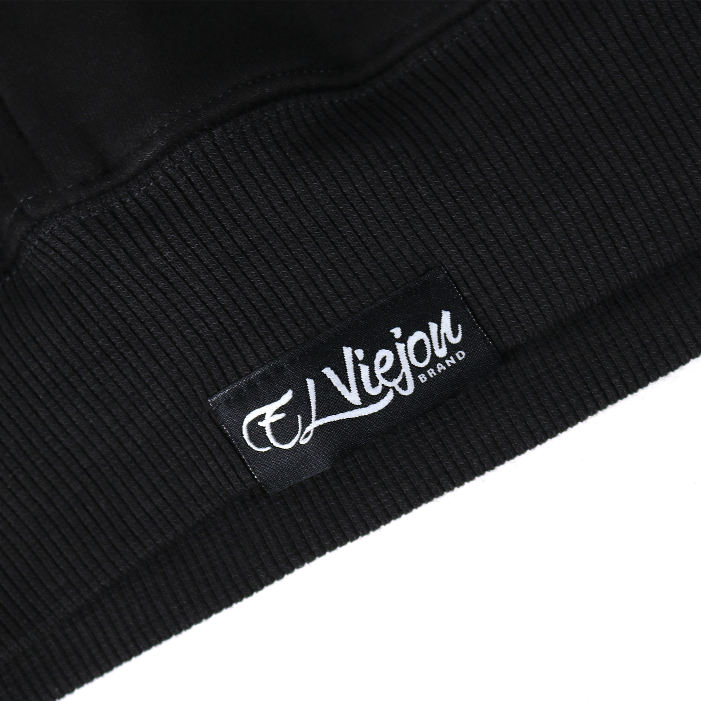 Close-up of a black cotton/poly fleece hoodie cuff with a white "El Viejou Brand" tag.