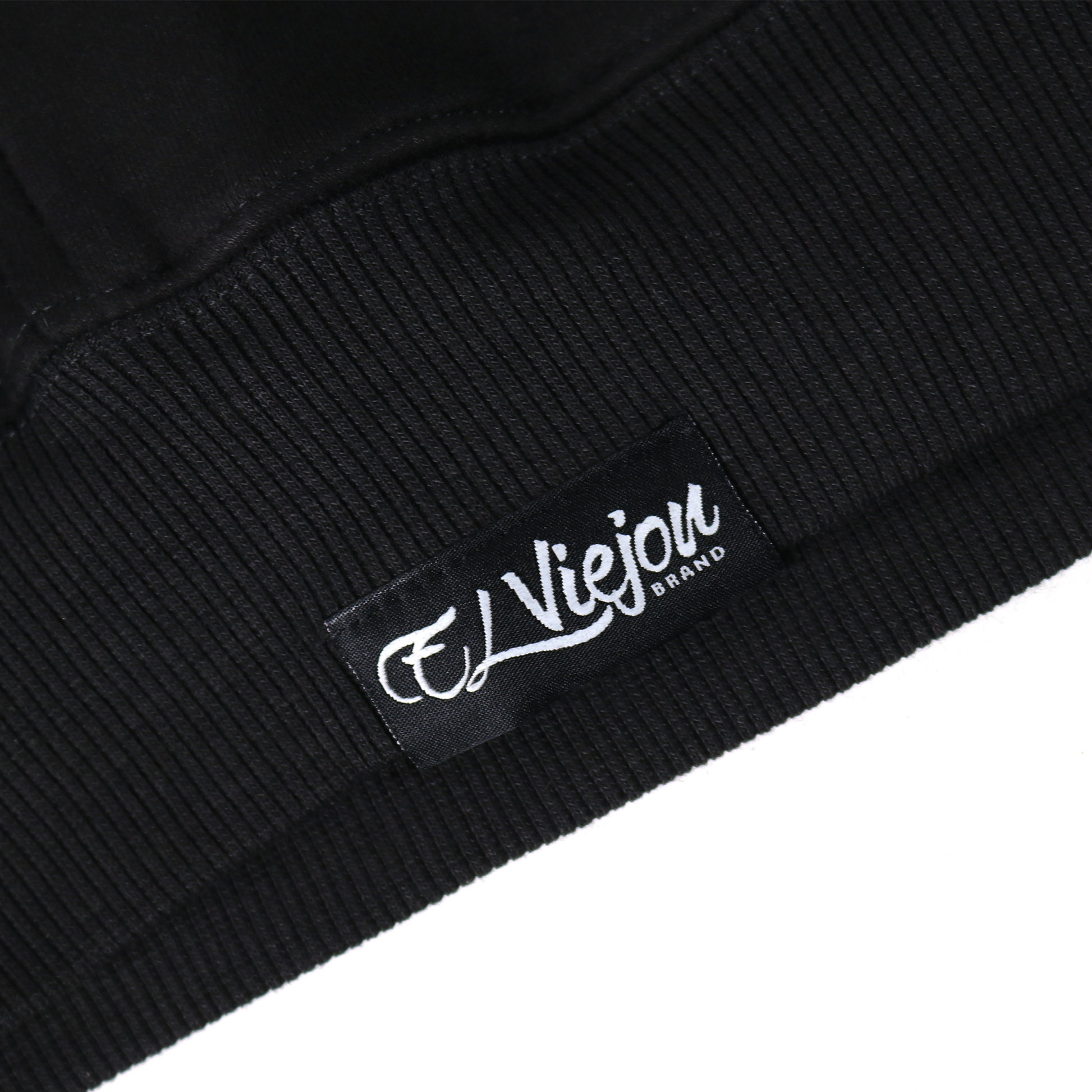 Close-up of a black cotton/poly fleece hoodie cuff with a white "El Viejou Brand" tag.