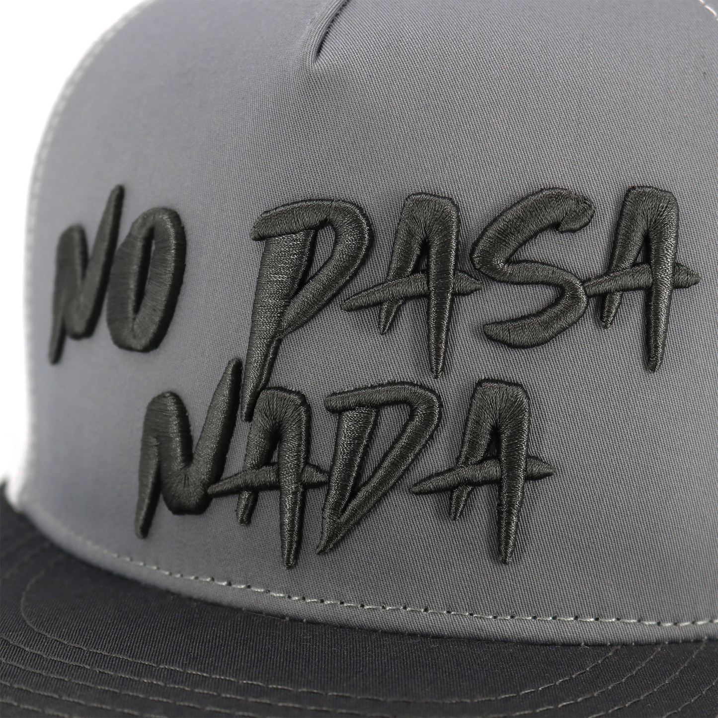 No Pasa Nada charcoal/grey/white flat visor hat with black embroidered text.
