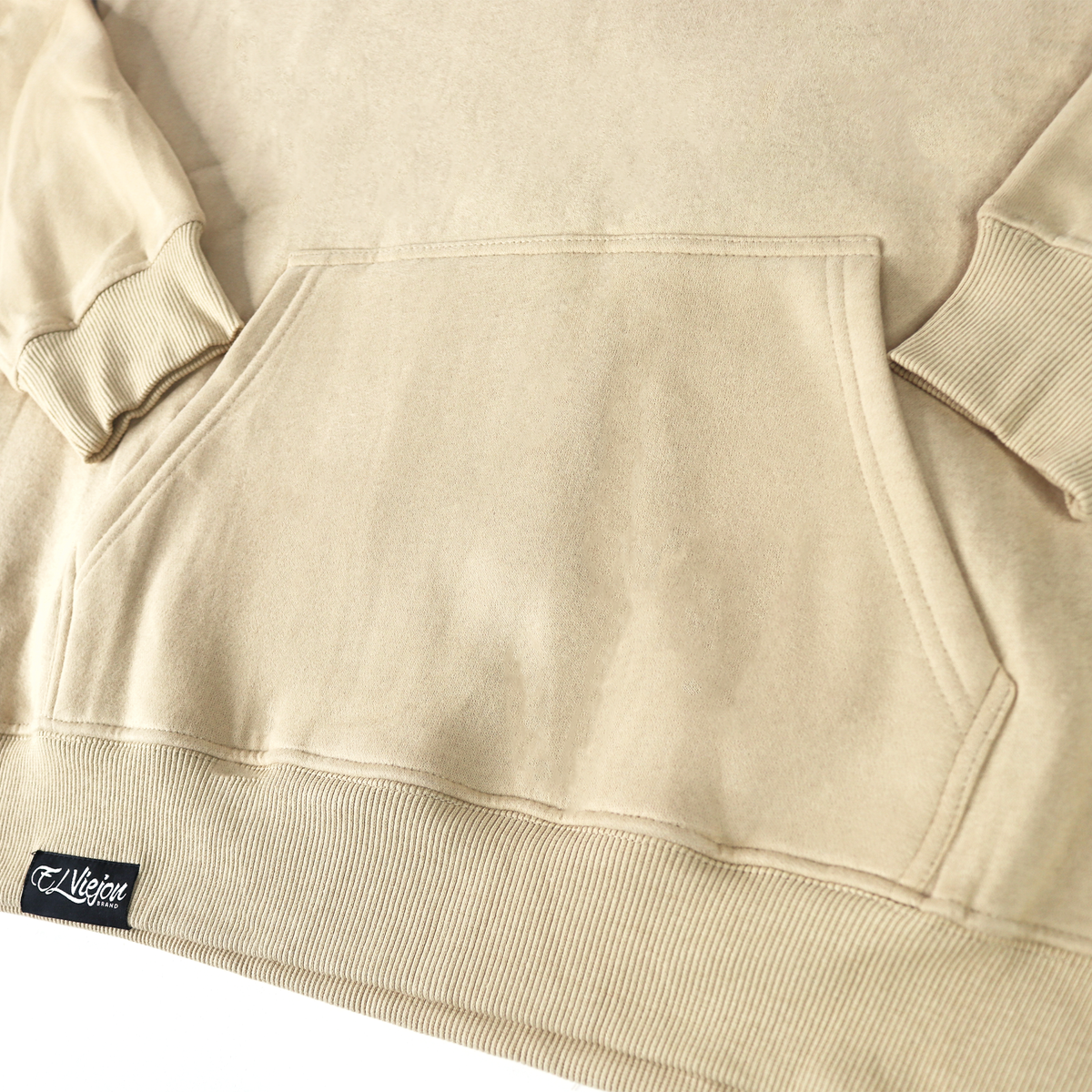 Close-up of a sand-colored cotton/poly fleece hoodie with a front pocket and screen-printed logo.